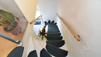 A modern staircase with dark carpeted steps and wooden handrails, leading to an upper floor.