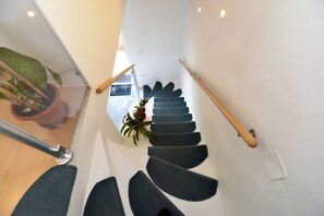 Stairs feature a unique wave-like design with carpeted steps and a potted plant at the top.