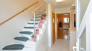 A staircase with blue steps and pink planters, leading to a room with a wooden door and a window. - Apartment 1873 (Pula)
