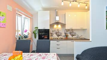 A compact kitchen with white cabinets, a gas stove, and a modern backsplash.