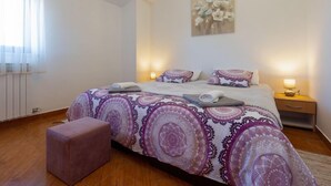 Un dormitorio con una cama grande, dos mesitas de noche con lámparas, una ventana con cortinas y un cuadro en la pared.