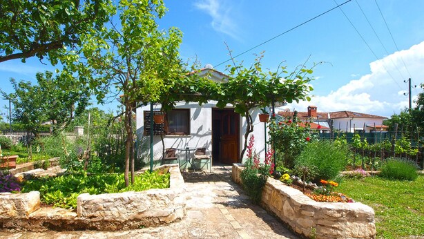 A stone pathway leading to a white building with a wooden door.