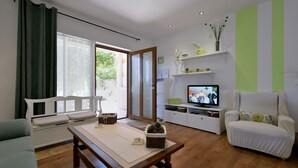 Un soggiorno con un divano, un tavolo di legno, un televisore e una parete a righe verdi.