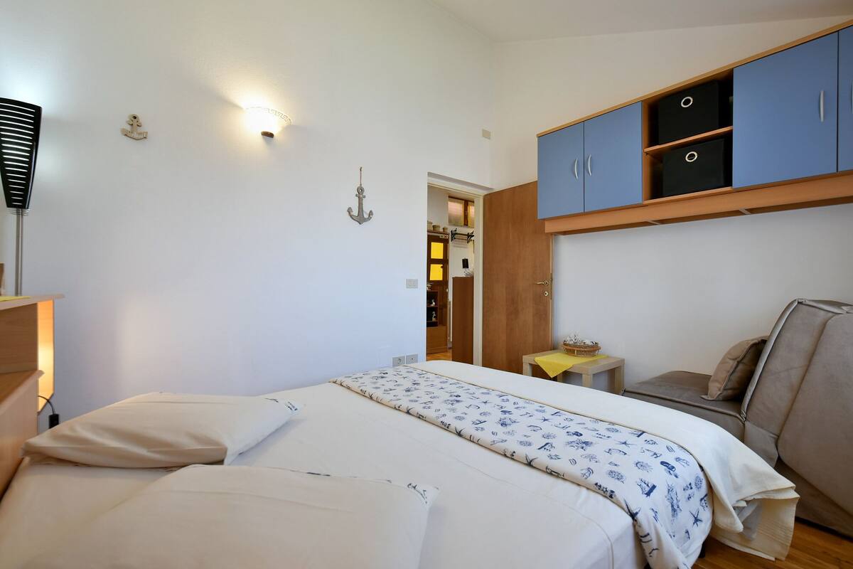 A bedroom with a bed, a desk, and a wardrobe.