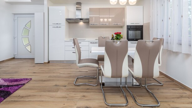 Una cocina moderna con armarios blancos, una isla central y una zona de comedor con mesa y sillas.