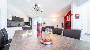 Ein moderner Essbereich mit einem Marmortisch, zwei Weingläsern, einer Blumenvase und einer Schale Erdbeeren.
