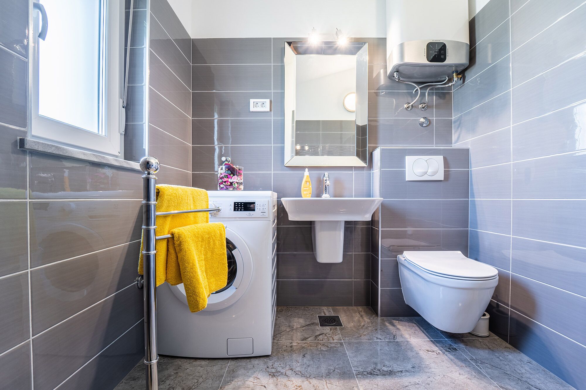 A compact bathroom with a washing machine, a sink, and a toilet.