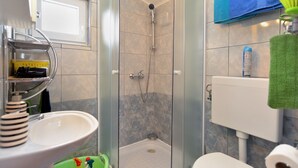 A modern bathroom with a glass-enclosed shower, a sink with a soap dispenser, and a toilet. - House 1884 (Fazana)