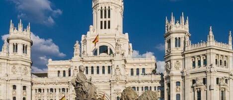 A grand building with a central tower, statues, and a flag.