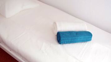 A single bed with white bedding and a folded blue towel.