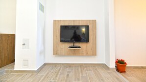 Una sala de estar moderna con un televisor de pantalla plana montado, un revestimiento de pared de madera y una planta en maceta.