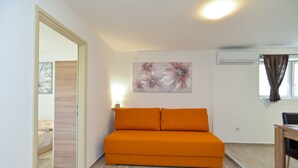 Una habitación con sofá, un cuadro, una lámpara y un equipo de aire acondicionado.