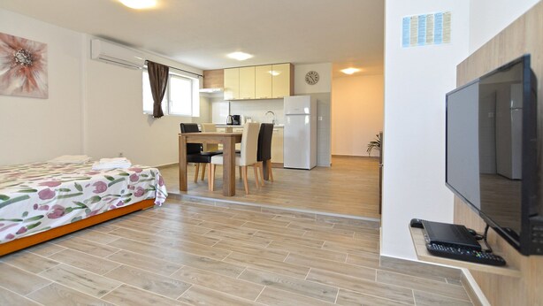 Un espacio habitable compacto con cama, zona de comedor, kitchenette y televisor.
