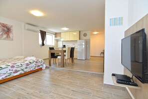 A compact living space with a bed, a dining area, a kitchenette, and a television. - Apartment 1890 (Marcana)