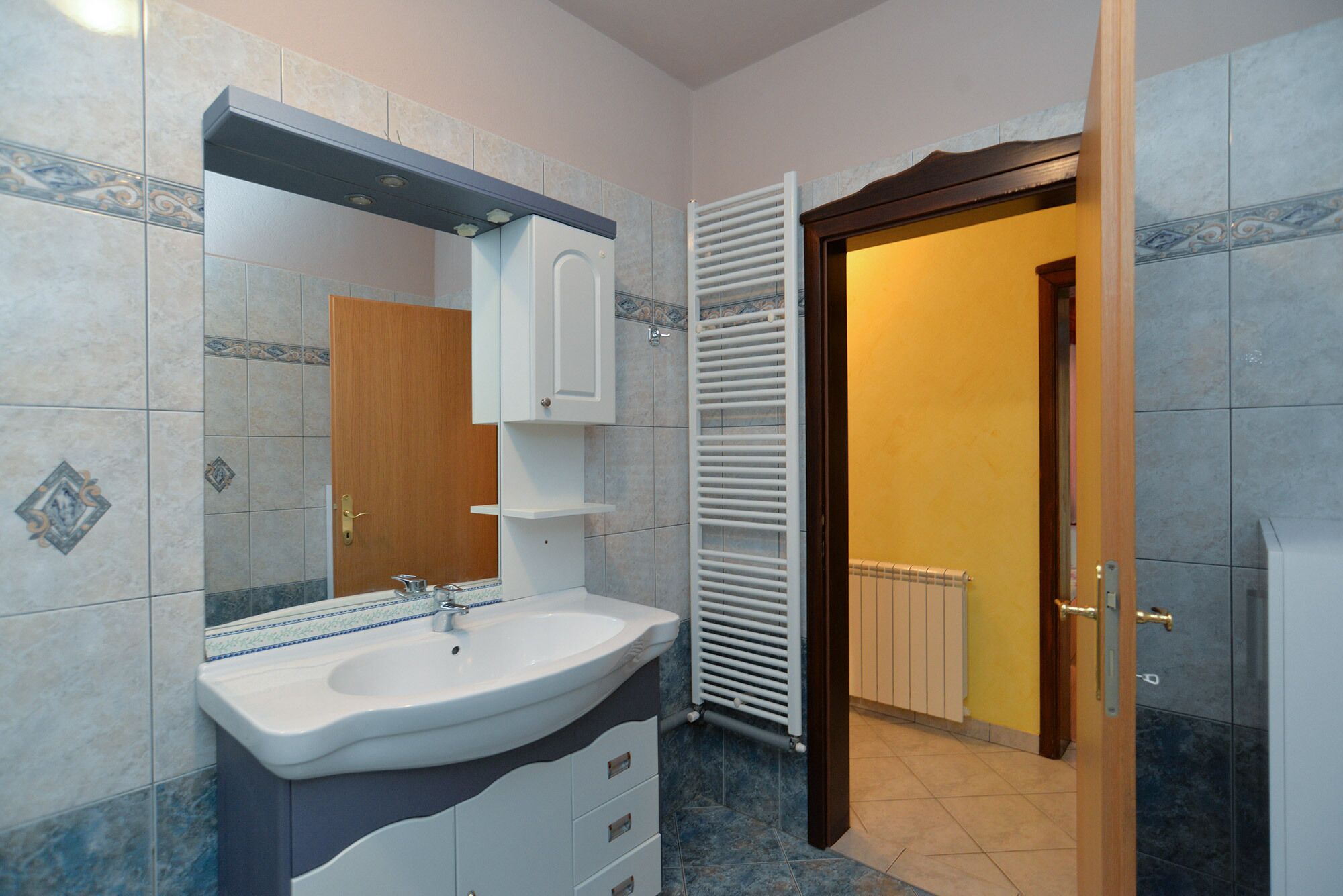A bathroom with a sink, mirror, cabinet, and towel rack.