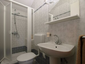 A bathroom with a shower, toilet, sink, and a towel rack. - Apartment 1895 (Marcana)