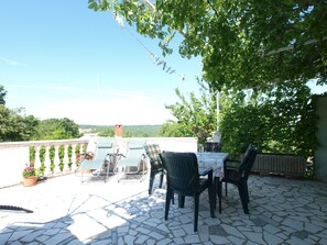 Eine Terrasse mit Sitzgelegenheit im Freien, Blick auf die Landschaft und ein Steinboden.