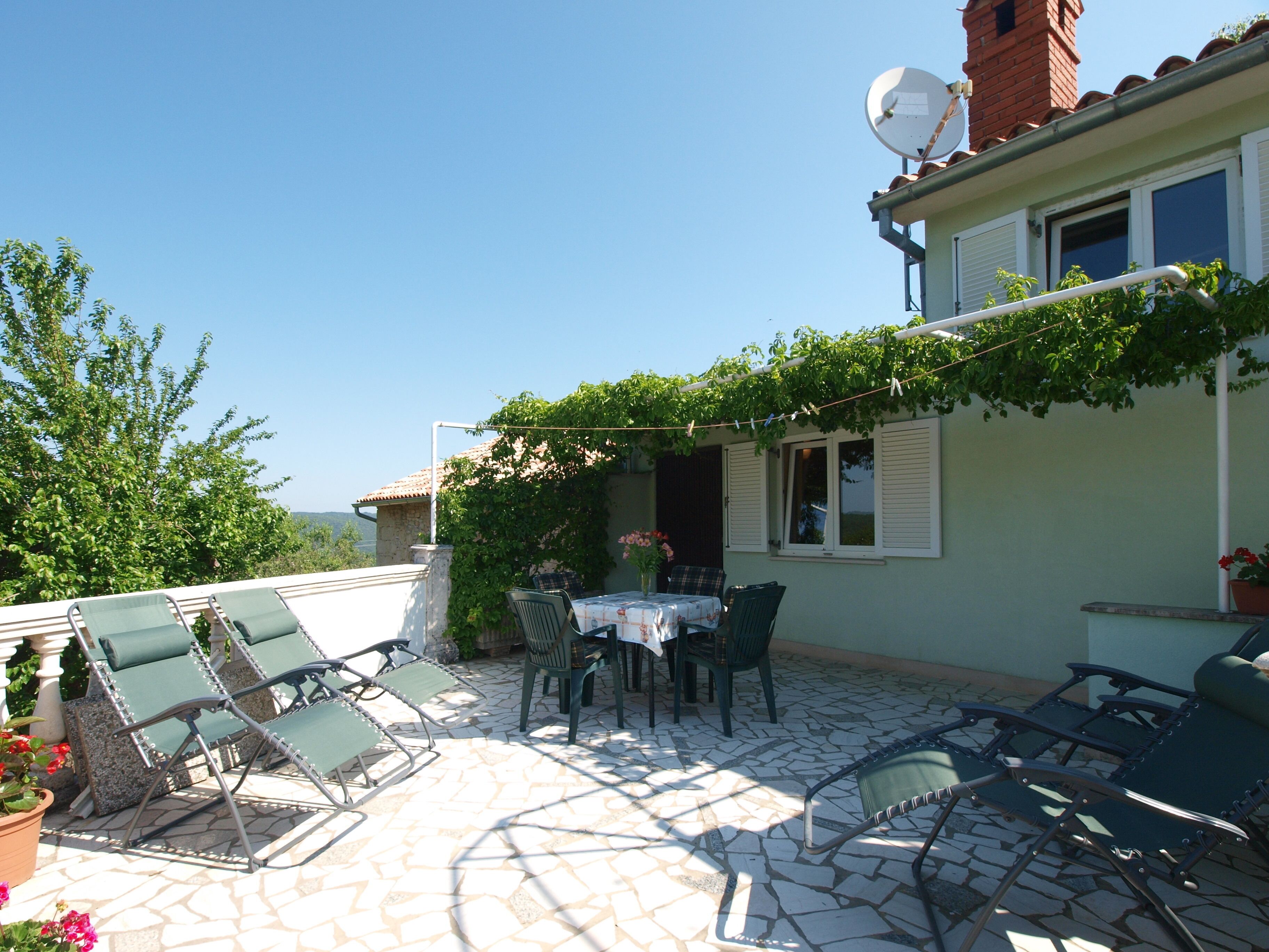 A patio with a table and chairs, a satellite dish, and a view of the countryside.