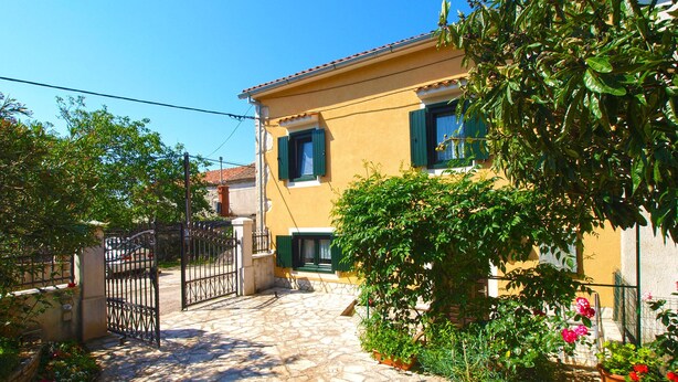 A yellow building with a stone pathway leading to a gated entrance.