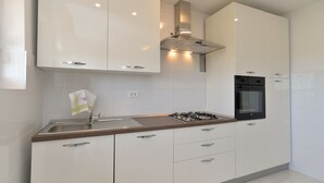 Een moderne keuken met witte kastjes, een gasfornuis, een oven en een roestvrijstalen spoelbak.