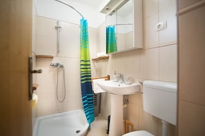 Un baño con ducha, lavabo e inodoro.