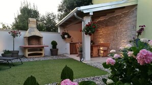 Un patio con horno de ladrillo, plantas en macetas y un muro de piedra.