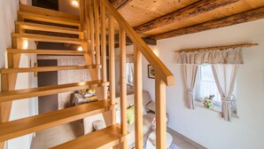 Una escalera de madera con techo rústico y una ventana con cortinas.