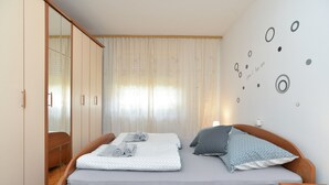 A bedroom with a bed, a wardrobe, and a wall with decorative circles. - Apartment 1905 (Pula)