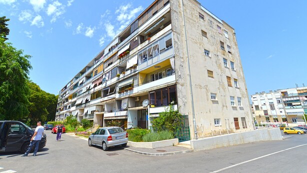 A multi-story residential building with balconies, a parking area, and a street view. - Apartment 1905 (Pula)