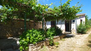 A stone building with a wooden fence and a garden area with green plants. - Apartment 1907 (Zminj)
