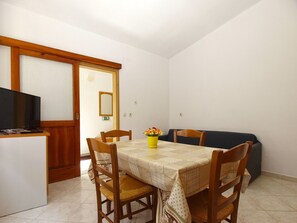 A dining area with a table, chairs, a sofa, a television, and a mirror. - Apartment 1907 (Zminj)
