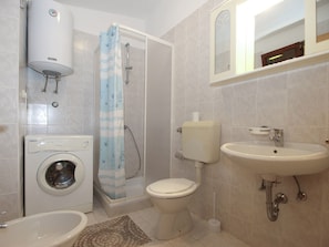 A bathroom with a washing machine, toilet, shower, and sink. - Apartment 1907 (Zminj)