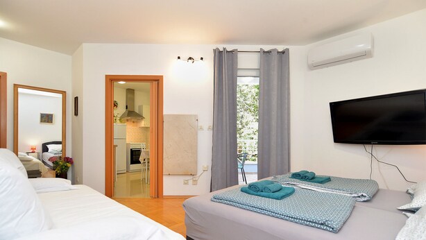 Ein Hotelzimmer mit zwei Betten, einem Fernseher und Blick auf die Küche und den Balkon.