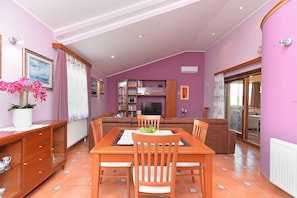 Relax in this stylish living space with a dining area, comfortable sofa, and large window offering a view of the outdoors.