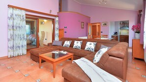 A living room with a brown sofa, a wooden coffee table, and a sliding glass door leading to another room. - Apartment 1917 (Rovinj)