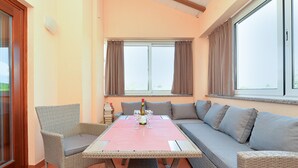 A room with a large window, a sofa, a table, and a chair. - Apartment 1917 (Rovinj)