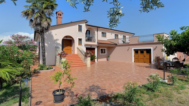 A two-story house with a red-tiled patio, a brick chimney, and a wooden door. - Apartment 1917 (Rovinj)