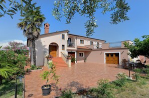 A two-story house with a red-tiled patio, a brick chimney, and a wooden door. - Apartment 1917 (Rovinj)