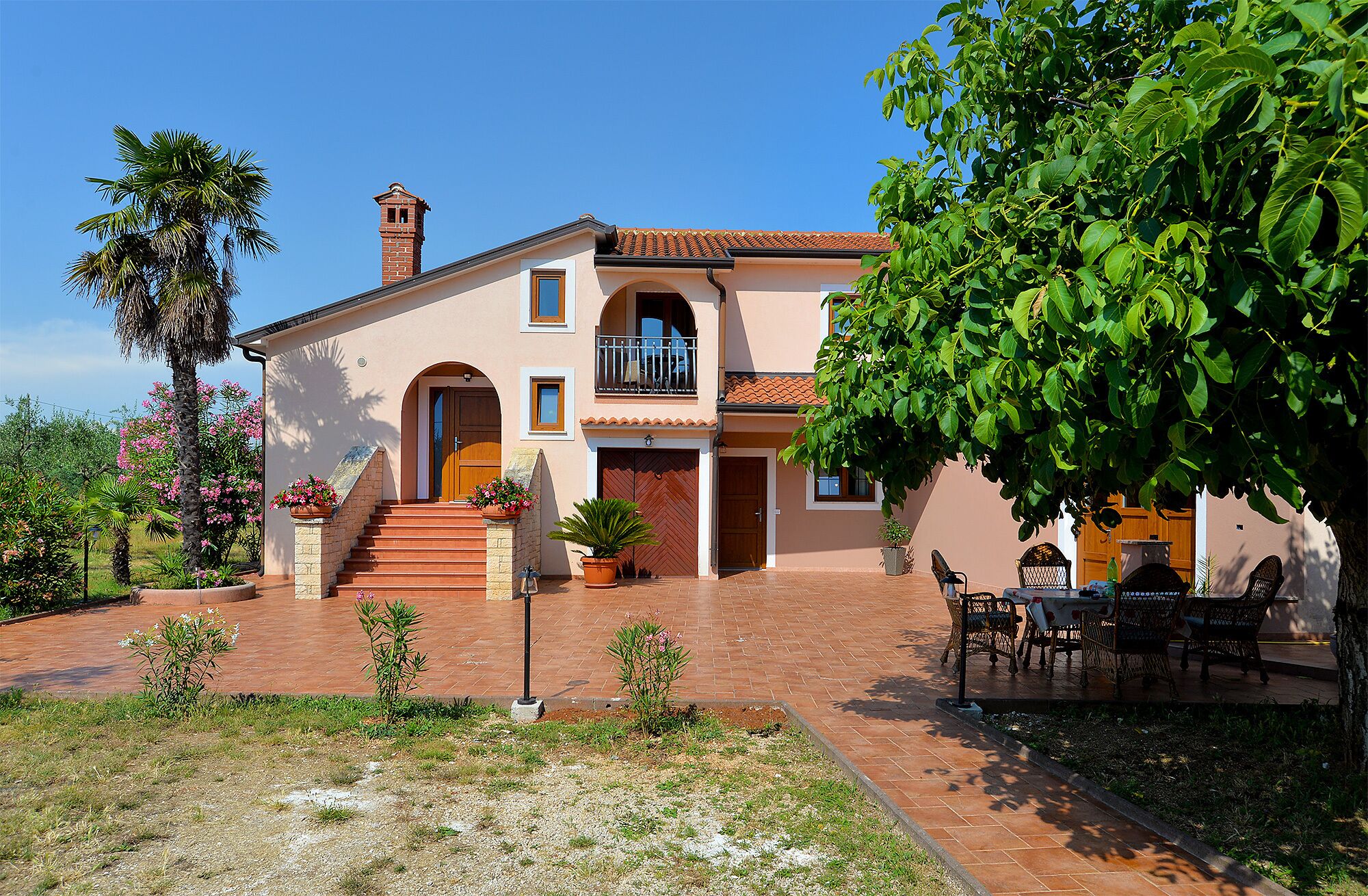 A two-story house with a balcony, a chimney, and a patio with outdoor furniture.
