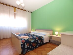 Um quarto com cama, mesa de cabeceira e cômoda.