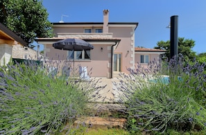 A two-story house with a stone facade, a tiled roof, and a swimming pool in the background. - House 1924 (Porec)