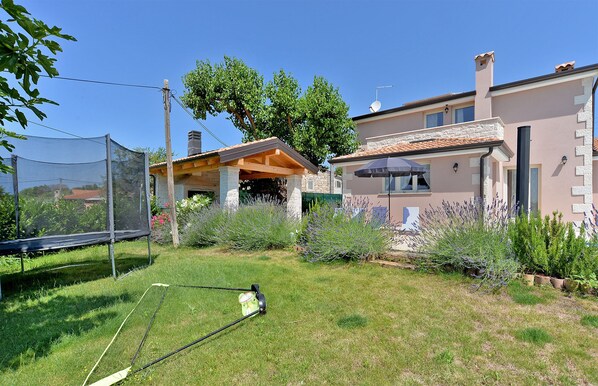 A residential property with a covered patio, a lawn, and a garden with lavender plants.