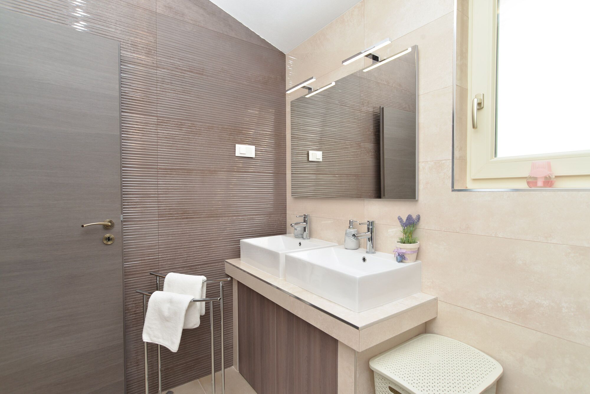 Une salle de bain moderne avec deux lavabos, une douche et un grand miroir.