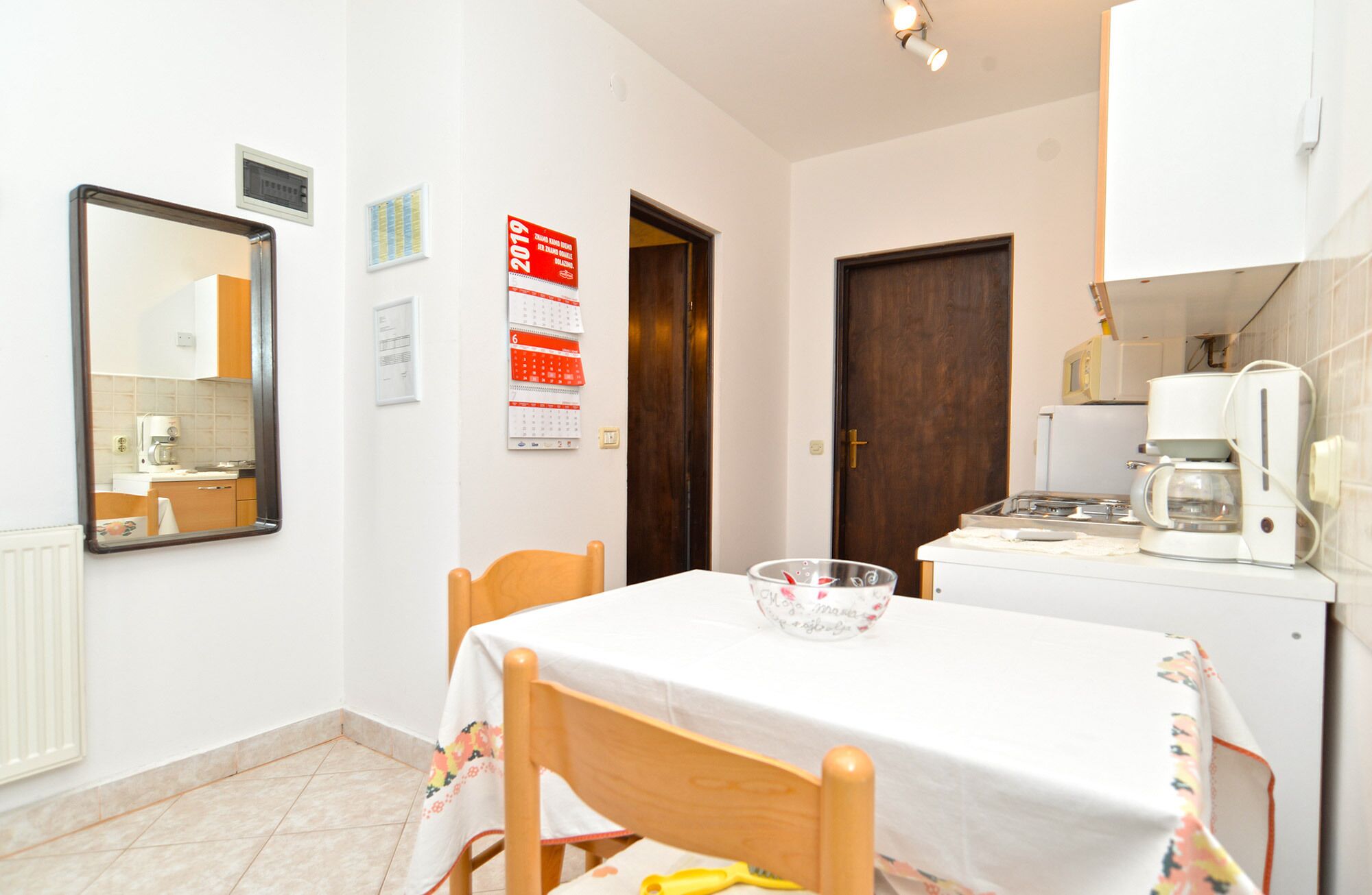 A small kitchen with a table and chairs, a refrigerator, and a coffee maker.