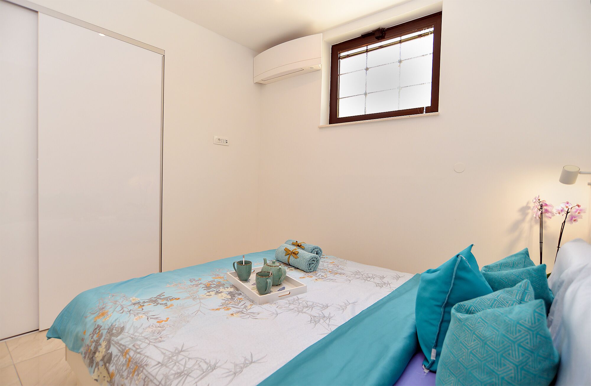 A bedroom with a bed, a window, and a bedside table with a tray.