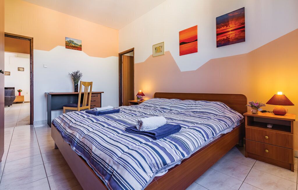 A bedroom with a large bed, bedside tables, a desk, and a chair.