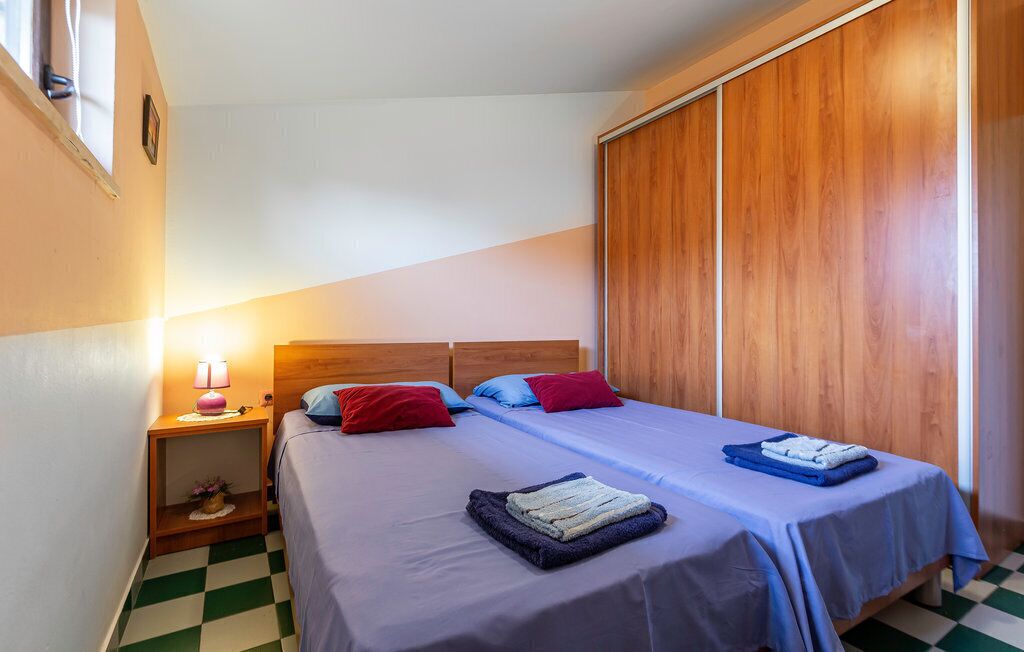 Ein Schlafzimmer mit zwei Betten, einem Holzschrank, einem Nachttisch mit Lampe und einem Schachbrettfußboden.