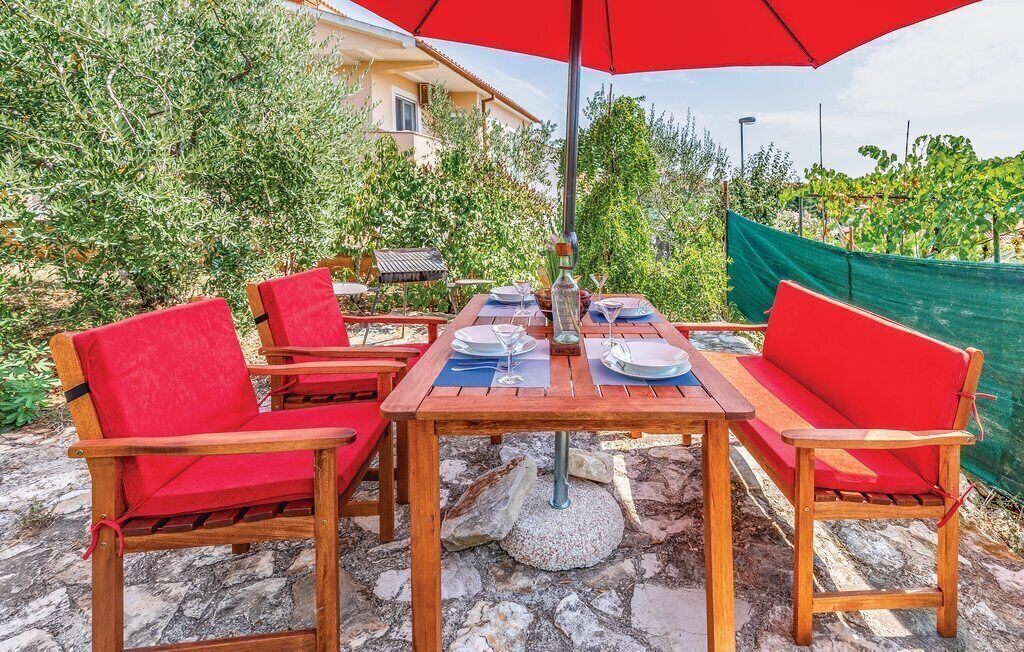 An outdoor dining area with wooden furniture and a red umbrella.
