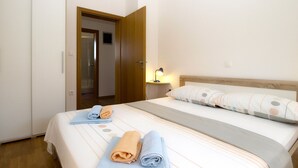 A hotel room with a bed, a nightstand with a lamp, a wardrobe, and a door leading to a bathroom. - Apartment 1932 (Fazana)