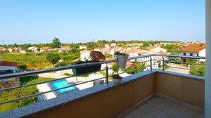 A balcony with a view of a residential area, a swimming pool, and a garden. - Apartment 1932 (Fazana)